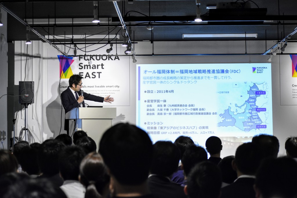 「オール福岡で⽬指すスマートシティ」について発表する事務局長 石丸